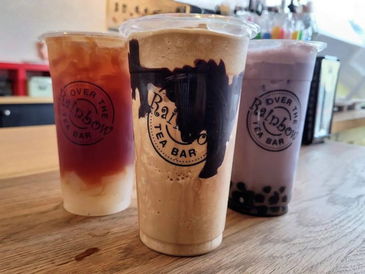 Three plastic bubble tea cups with taro, chocolate and fruit tea varieties at Over The Rainbow Tea Bar, a Tea House in Renton