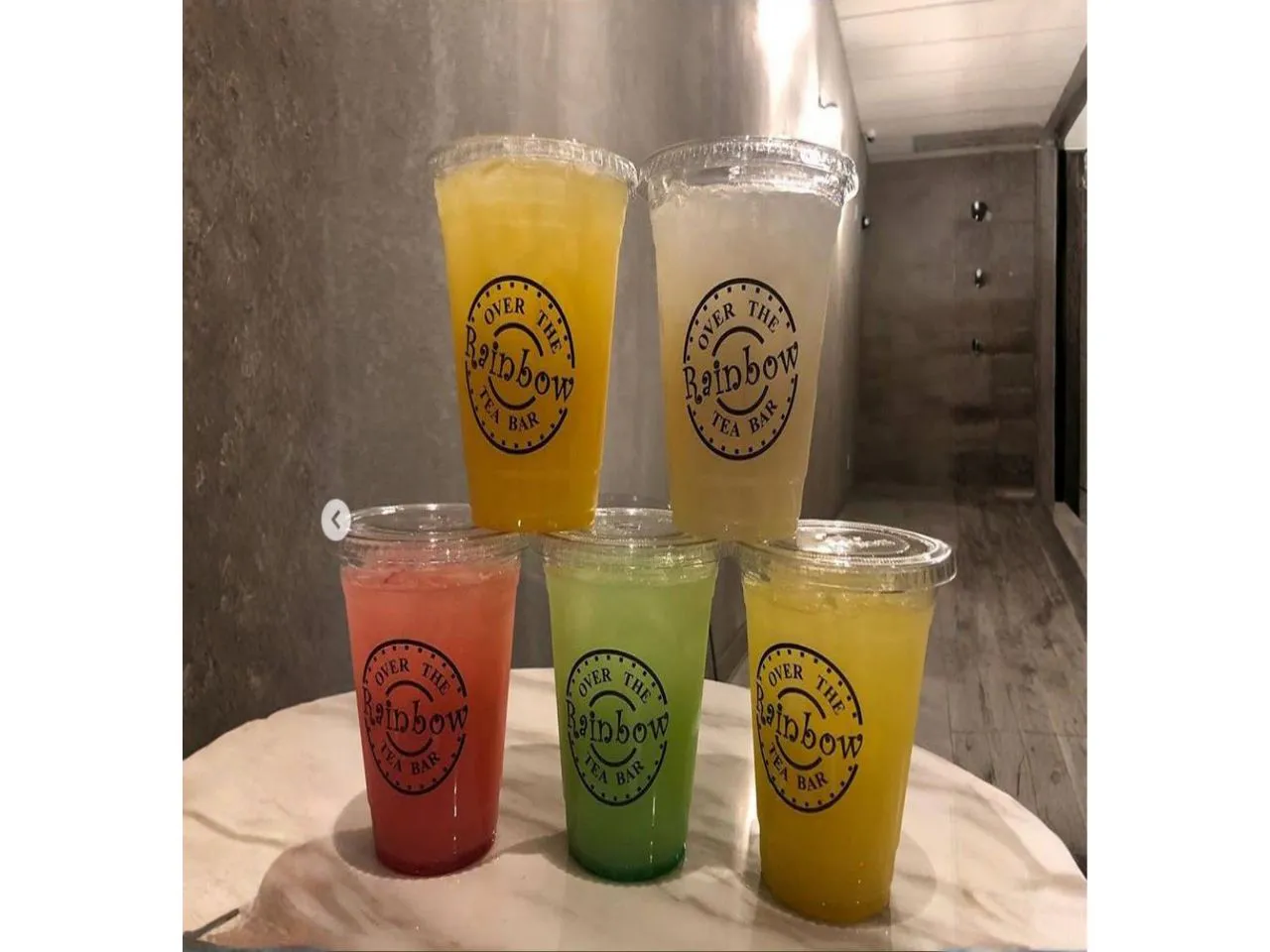 Five vibrant colorful fruit iced tea cups stacked on marble table at Over The Rainbow Tea Bar, a Tea House in Renton